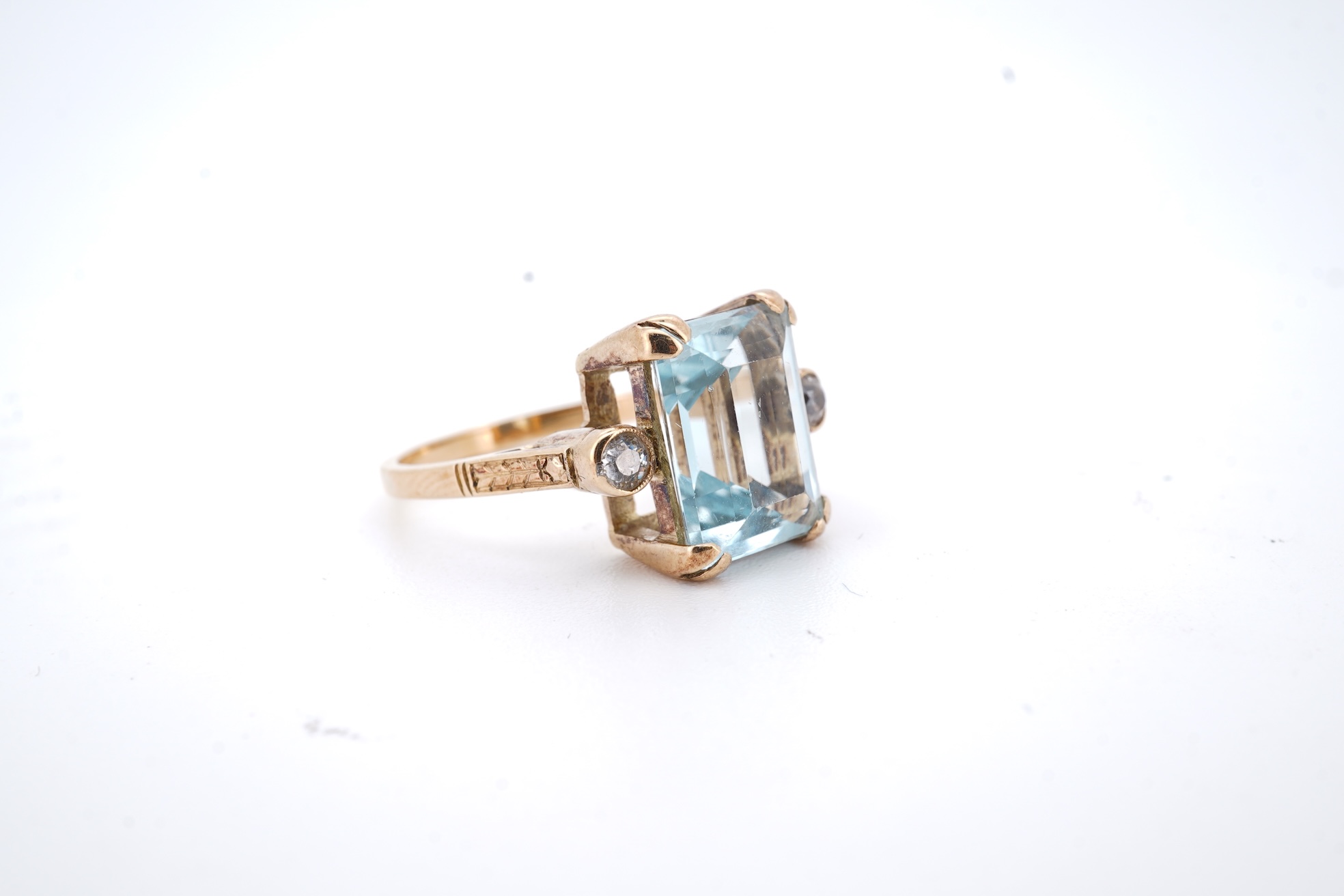 A yellow metal and single stone emerald cut aquamarine set ring, with two stone diamond set shoulders, size M, gross weight 4.2 grams.